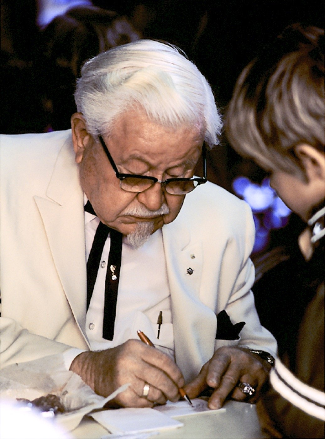 El coronel Harland Sanders con su traje blanco firmando un autógrafo